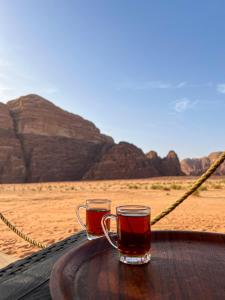 zwei Gläser Tee auf einem Tisch in der Wüste in der Unterkunft Wadi Rum Mirror Camp in Wadi Rum