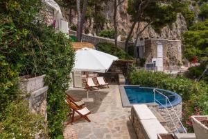 a pool with an umbrella and chairs next to a house at Villa Roccia Di Mare in Capri