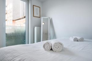 a bedroom with a white bed with towels on it at Trendy en stijlvol appartement aan zee - 4p in De Haan