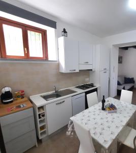 a kitchen with a sink and a table with chairs at Appartamento IL Tulipano in Brezzo