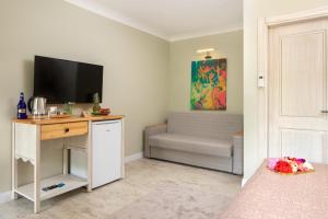 a bedroom with a desk with a television and a couch at Orange Garden Hotel Akyaka in Akyaka