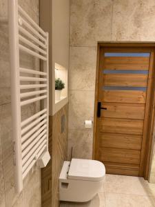 łazienka z toaletą i drewnianymi drzwiami w obiekcie Rezydencja Biały Dom w mieście Ustrzyki Dolne