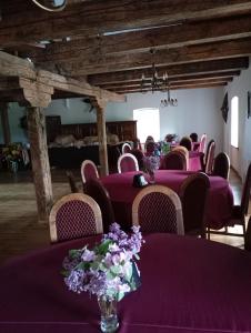 ein Zimmer mit lila Tischen und Stühlen mit lila Blumen darauf in der Unterkunft Gazdų Vandens Malūnas in Navininkai
