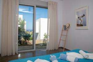 Un dormitorio con una cama azul y una gran ventana. en Villa Kassandra, en Pitsidia