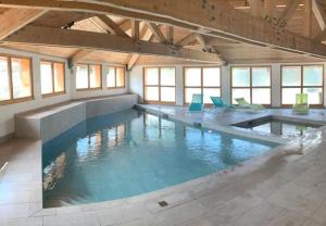 a large indoor swimming pool with blue chairs in it at La TANIÈRE du LOUP in Le Dévoluy