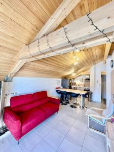 un sofá rojo en una sala de estar con mesa en La TANIÈRE du LOUP, en Le Dévoluy