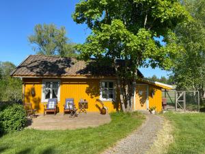 a yellow house with a patio in front of it at Farm stay in cozy cabin at Vestre Kinn in Ørje