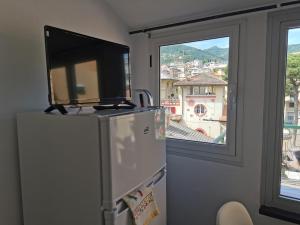 a refrigerator with a tv on top of it in front of a window at VERDEACQUA Flat in Rapallo +15 photos