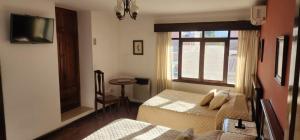 a bedroom with two beds and a window and a table at Hotel Carmen in Tarija