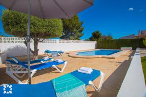 patio z 2 krzesłami, parasolem i basenem w obiekcie Villa Los Almendros by Abahana Villas w mieście Calpe