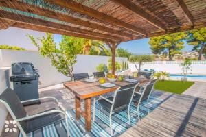 patio z drewnianym stołem, krzesłami i sprzętem do grillowania w obiekcie Villa Los Almendros by Abahana Villas w mieście Calpe