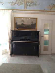 - un piano noir dans une pièce ornée d'une peinture murale dans l'établissement L'Orto di Sant'Andrea, à Pise