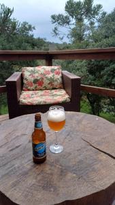 uma garrafa de cerveja sentada numa mesa de madeira com um copo em Hospedagem Cabanas do Lago Urubici em Urubici