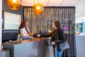a man and a woman shaking hands at a desk at ibis Styles Hotel Brussels Centre Stéphanie in Brussels