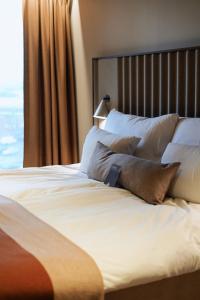 a bed with white sheets and pillows next to a window at Clarion Hotel Karlatornet in Gothenburg