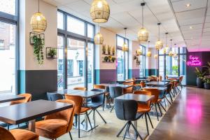 een rij tafels en stoelen in een restaurant met ramen bij ibis Styles Hotel Brussels Centre Stéphanie in Brussel