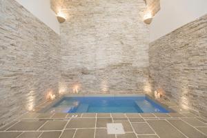 a swimming pool in a room with a brick wall at Guerrieri Suites & Spa in Campi Salentina