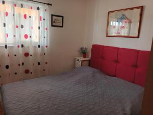 a bedroom with a red bed and a curtain at Apartman Karla in Makarska