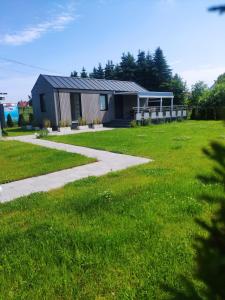 a house in a field with a sidewalk and grass at Słoneczny Zakątek nad Doliną Słupi in Grabno