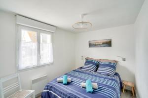 a bedroom with a bed with blue pillows and a window at À 300m de la Greve Blanche - Appartement pour 6 in Le Guilvinec