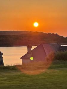 a sunset over a barn with the sun setting in the background at Lough Erne Resort Villa in Ballycassidy