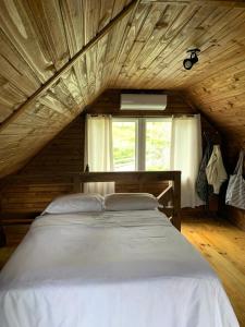um quarto com uma grande cama branca e uma janela em Hospedagem Cabanas do Lago Urubici em Urubici
