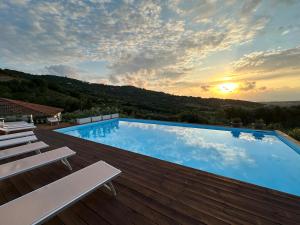 une grande piscine avec un coucher de soleil en arrière-plan dans l'établissement Il Poggio del Cilento Country House, à Agropoli