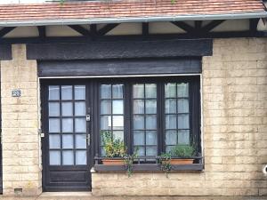 ein Fenster auf einem Backsteingebäude mit Topfpflanzen in der Unterkunft Appartement RDC Centre Cabourg in Cabourg