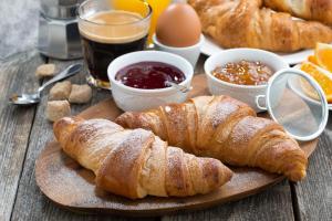 a wooden table with croissants and other breakfast foods at H+ Hotel Bremen in Bremen