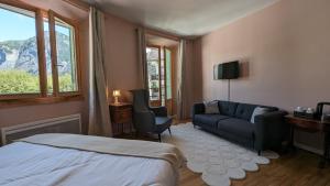 ein Schlafzimmer mit einem Bett, einem Sofa und einem Fenster in der Unterkunft Sport'Hotel-Aparthotel de Milan in Le Bourg-dʼOisans