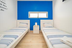 2 łóżka w pokoju z niebieską ścianą w obiekcie Hostel Supremo w Armação de Pêra
