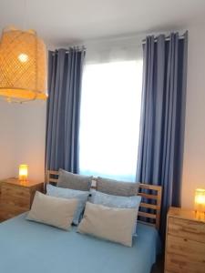a bedroom with blue curtains and a bed with pillows at Aegina Port Apt 2-Διαμέρισμα στο λιμάνι της Αίγινας 2 in Aegina Town