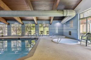 a swimming pool with two hot tubs in a room with windows at Winter Park Condo w/ Resort Shuttle On-Site! in Winter Park
