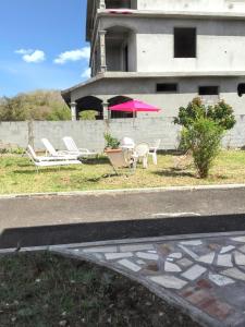 un gruppo di sedie e un ombrellone rosa di fronte a un edificio di 3 bedrooms apartement at Calodyne 300 m away from the beach with enclosed garden and wifi a Calodyne