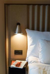 een boek op een nachtkastje naast een bed met een lamp bij Clarion Hotel Karlatornet in Göteborg