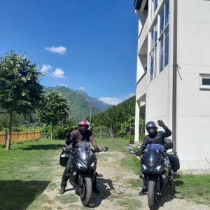 Dos personas en motocicleta estacionadas al lado de un edificio en Guest House Artjon, en Fierzë