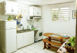 cocina con armarios blancos y mesa de madera en Appartement d'une chambre avec jardin amenage et wifi a Baie Mahault, en Baie-Mahault