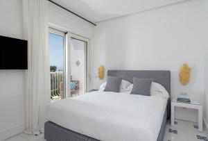 ein Schlafzimmer mit einem großen weißen Bett und einem Fenster in der Unterkunft Boutique Hotel Casa Mariantonia in Anacapri