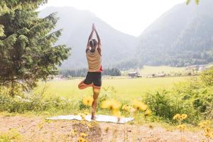 a person doing a yoga pose in a field at Bio Natur Refugium Blaslahof **** in Valle Di Casies