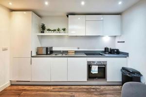 a kitchen with white cabinets and a stove top oven at Modern 2-bedroom kingsize apartment city centre in Birmingham