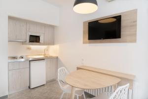 eine Küche mit einem Holztisch sowie einem kleinen Tisch und Stühlen in der Unterkunft Sol Lunamar Palmanova Apartamentos - Adults Only in Palmanova
