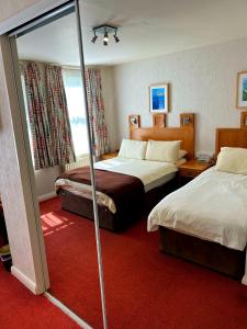 una camera d'albergo con due letti e una finestra di Welbeck Hotel & Apartments a Douglas