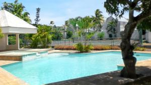 a large swimming pool with a tree in the foreground at 3 bedrooms house at Grand Baie 500 m away from the beach with private pool enclosed garden and wifi in Grand-Baie