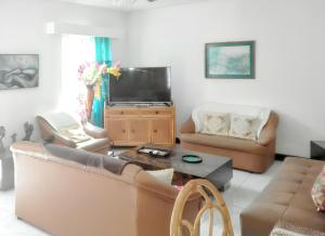 a living room with a couch and a tv at 3 bedrooms house at Grand Baie 500 m away from the beach with private pool enclosed garden and wifi in Grand-Baie