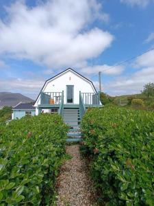 a small white house with a balcony in a field at Greenhills Cottage -Overlooking Slieve League in Kilcar