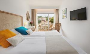 a bedroom with a bed with a television and a table at Hotel Apartamentos Cala Santanyi in Cala Santanyi