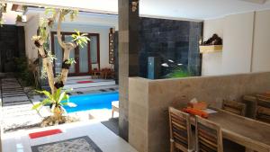 a villa with a swimming pool and a dining room with a table at Nyaman Guest House in Sanur