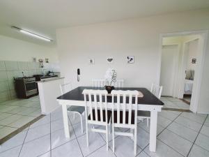 eine Küche mit einem weißen Tisch und weißen Stühlen in der Unterkunft Residencial Cristina's-Apartamentos de 2-3 Quartos equipados com WiFi Garagem-Excelente Localização in Lages