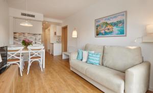 a living room and kitchen with a couch and a table at Hotel Apartamentos Cala Santanyi in Cala Santanyi