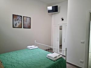 a white room with a bed with a green blanket at Vagabondando travel house in LʼAquila